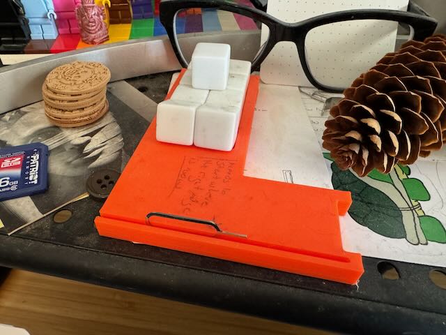 an orange l-shaped piece of plastic with many blank white dice in it.